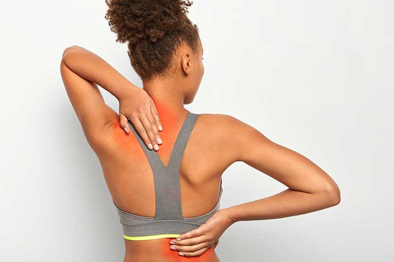 Woman holding her neck and lower back in pain from auto accident