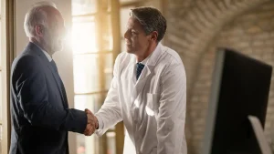 A car accident doctor and lawyer shake hands, collaborating to support a patient’s case.