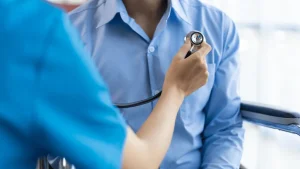 A doctor examining a patient’s chest with a stethoscope after a car accident